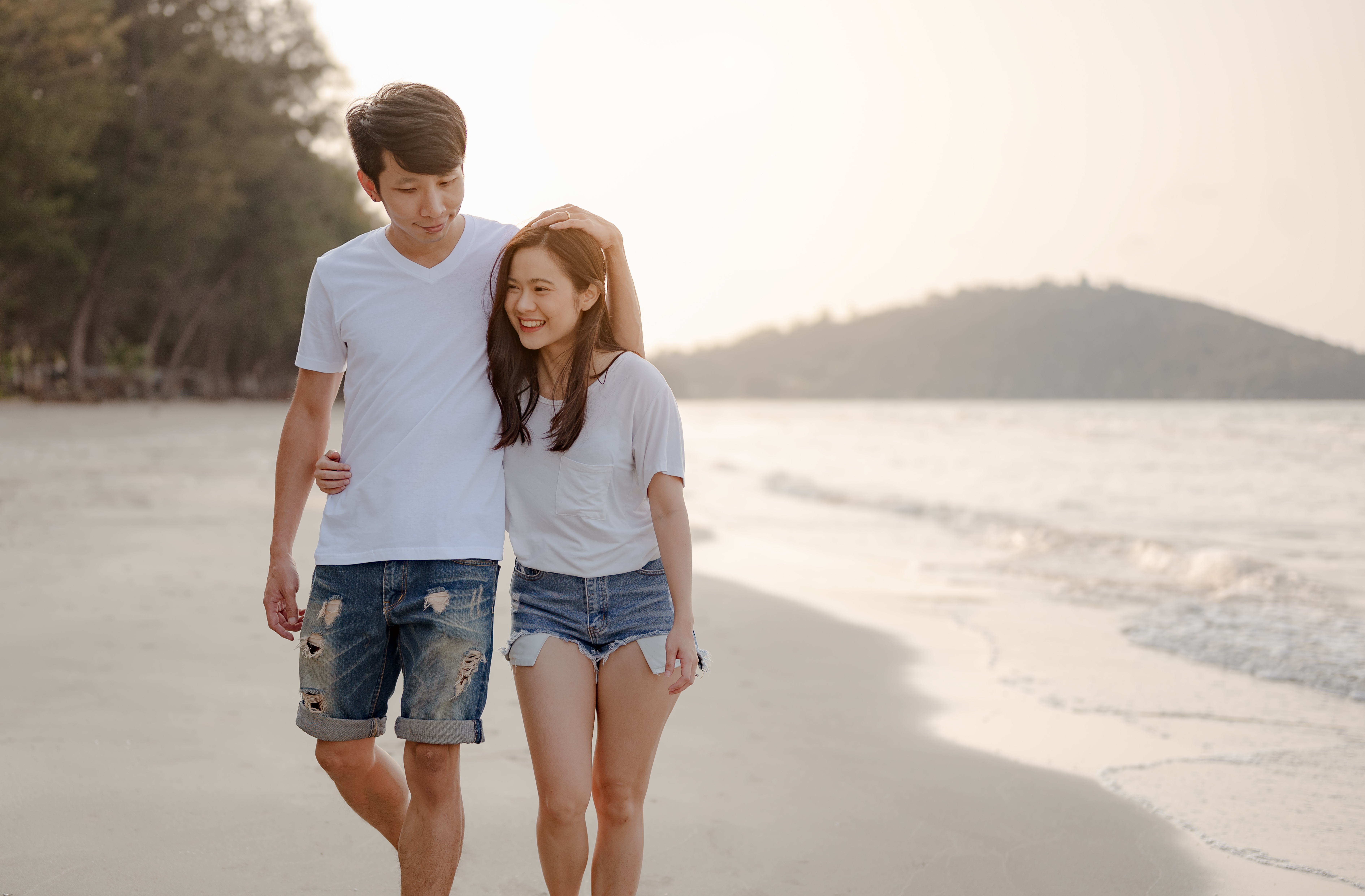 Romantic couple walking hugging each other while at beach at sunrise, plan life insurance