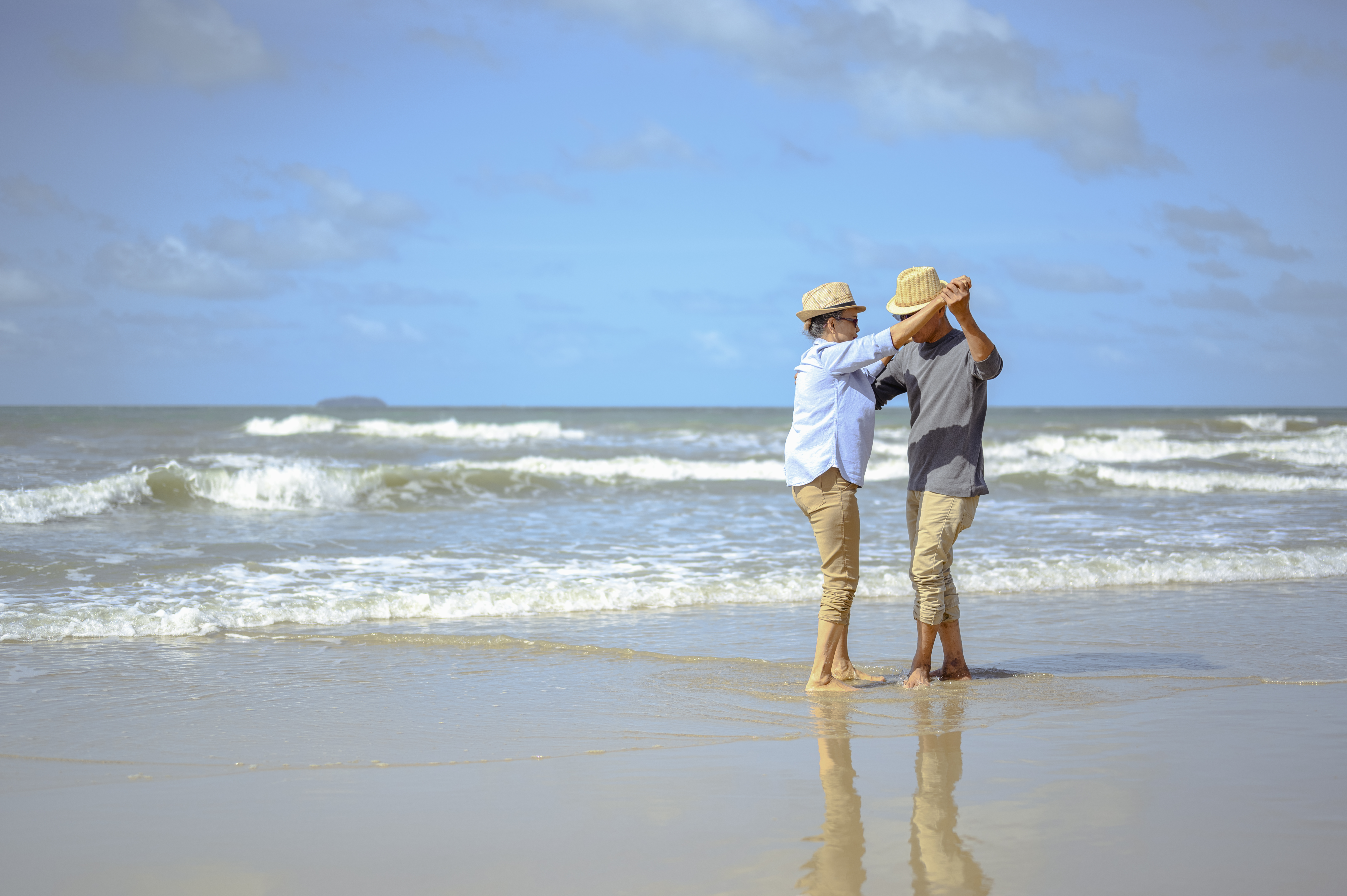 Senior couple dancing on the beach on good days, plan life insurance at retirement concept.